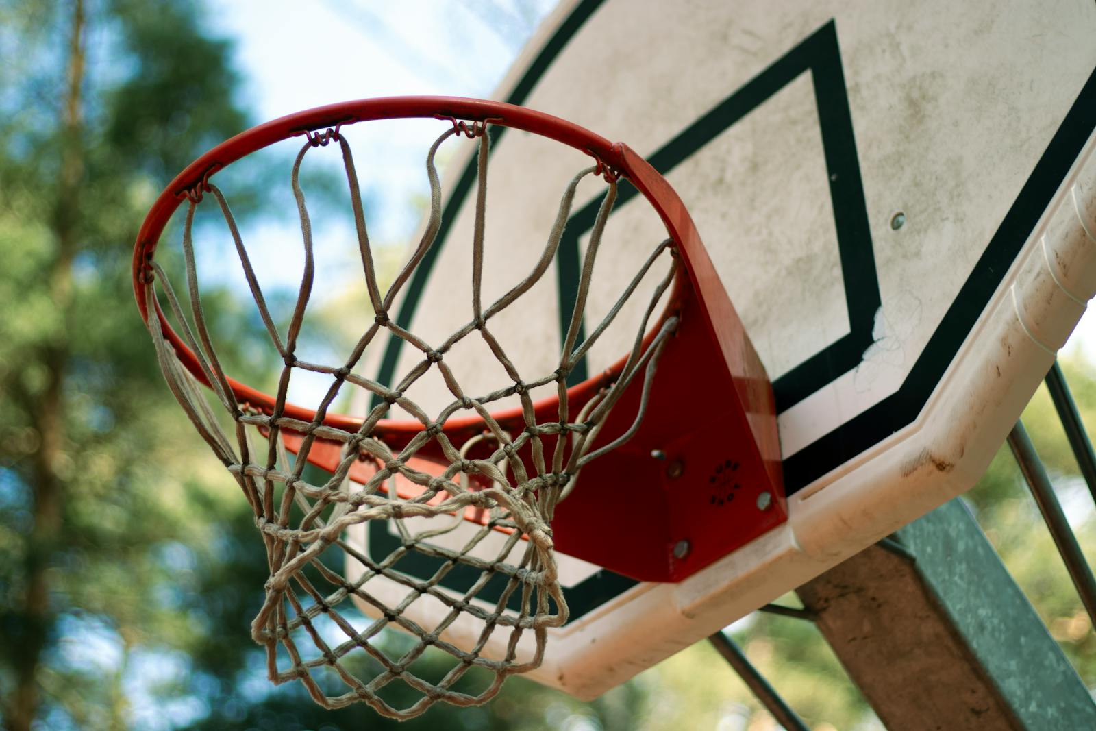 A detailed view of a basketball hoop and net against a blurred outdoor background, emphasizing a sporty feel.
